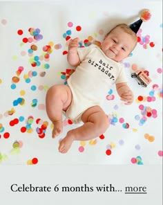 a baby with a party hat laying on it's back in front of confetti