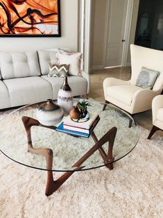 a living room filled with furniture and a glass top table in front of a white couch