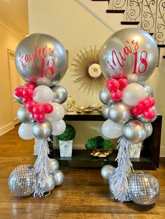 two silver balloons with pink and white streamers are on display in front of a staircase