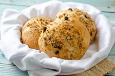 three loaves of bread sitting in a white bowl on a blue tablecloth napkin