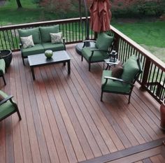 a wooden deck with green furniture and an umbrella