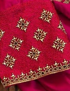 a red and gold cloth on top of a wooden table next to a pink blanket