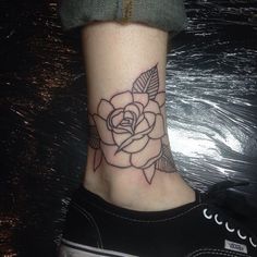 a black and white rose tattoo on the ankle