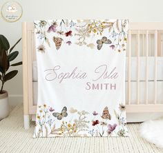 a baby crib with a personalized name and butterflies on the blanket in front of it