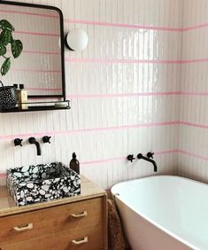 a white bath tub sitting next to a wooden dresser under a mirror in a bathroom