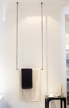 a bathroom with white walls and black towels hanging from the hooks on the wall next to it