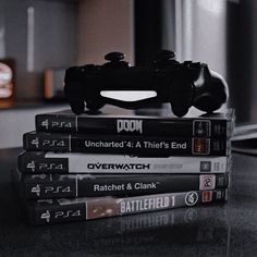 a stack of video games sitting on top of a table next to a remote control