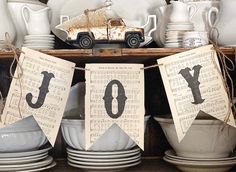 a shelf filled with dishes and plates covered in paper bunting that spell out the word joy