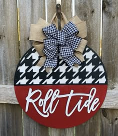 a sign that says roll tide hanging on the side of a wooden fence with a bow