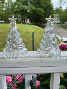 two glass christmas trees sitting on top of a window sill