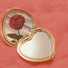 a heart shaped mirror with a red rose in it