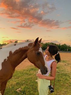 a woman standing next to a brown and white horse