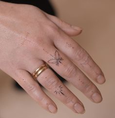 a woman's hand with a butterfly tattoo on her left ring, and a gold wedding band