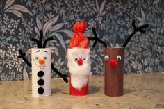 three toilet paper roll crafts with faces and noses, one is made to look like snowmen