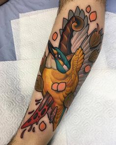 a colorful bird tattoo on the arm