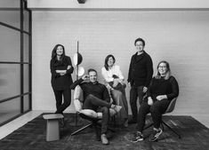 four people are posing for a photo in front of a white brick wall and floor