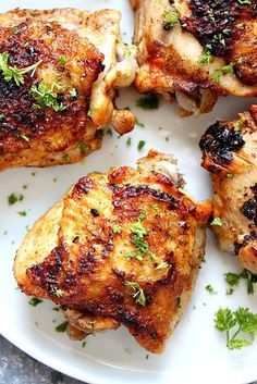 four pieces of chicken on a plate with parsley sprinkled around the edges