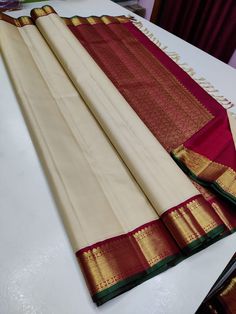 the white and red saree is laying on top of the table with gold trim