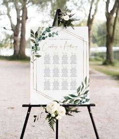 a sign with greenery and white flowers on it