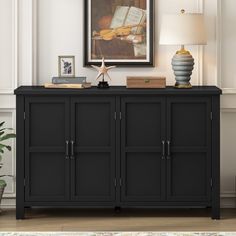 a black sideboard with two books and a lamp