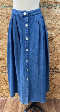 "This is a great vintage button down denim skirt, circa 1980s. It has full skirt styling with pleats and two pockets. Made in USA. 100% cotton. It is in overall good vintage condition. The only flaw noted is that the right side of the skirt seems a little faded. Labeled a vintage size 8, but Most likely would fit a modern size XS/ S. Please check measurements and condition notes below: Waist: 12.5\"-14\" Overall total length: 36\" Please ask questions through Etsy messages. Since this is a vinta Dark Wash Button-up Cotton Skirt, Button-up Denim Blue Cotton Skirt, Denim Blue Button-up Cotton Skirt, Medium Wash Button-up Cotton Skirt, Cotton Skirt With Buttons In Medium Wash, Vintage Cotton Skirt In Dark Wash, Vintage Buttoned Denim Skirt For Spring, Vintage Denim Skirt With Button Closure, Vintage Medium Wash Skirt With Pockets