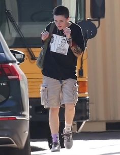 a young man walking down the street in front of a school bus