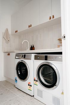 a washer and dryer in a small room with white cabinets on the wall