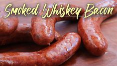 two sausages on a wooden table with the words smoked whiskey bacon over it's image