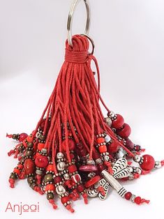 a red tasseled keychain with beads and charms hanging from it's side