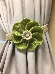 a crocheted flower is attached to the back of a drapes with buttons