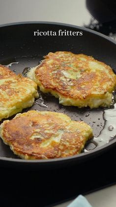 three fritters cooking in a skillet on the stove