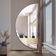 a large round mirror sitting on the side of a wall next to a vase filled with flowers