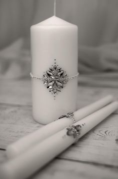 a white candle with a chain around it sitting next to two toothbrushes on a wooden table