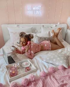 a woman laying in bed with a laptop on her lap and phone to her ear