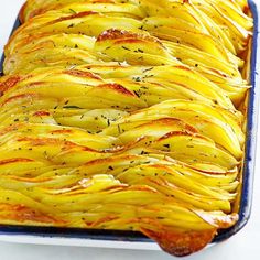 a casserole dish filled with potatoes covered in herbs and seasoning sits on a white surface