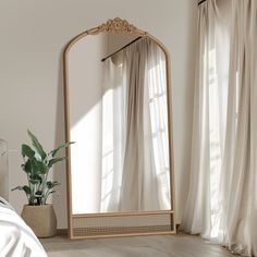 a large mirror sitting on top of a wooden floor next to a plant in a vase