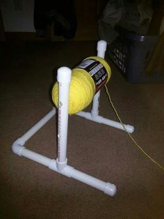 a yellow ball of yarn sitting on top of a white pole with two poles attached to it