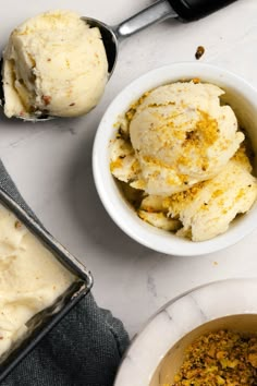 two scoops of ice cream next to an empty bowl on a marble counter top