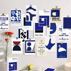 there are many blue and white posters on the wall above a vase with flowers in it