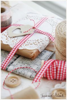 some twine and scissors are on top of the table next to wrapping paper with lace