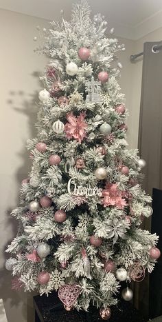 a white and pink christmas tree with ornaments