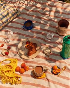 a table topped with plates of food and cups of coffee on top of a blanket