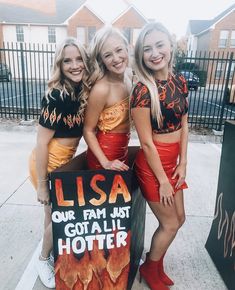 three girls dressed in costumes standing next to a sign that sayslisa our fam just got a lil hotter