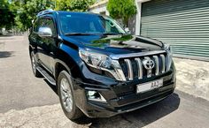 a black toyota land cruiser parked in front of a garage door on the side of a road