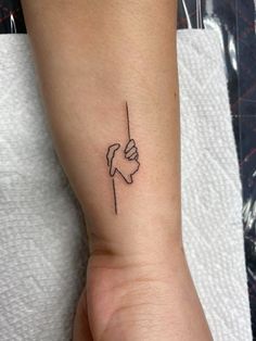 a woman's arm with a small tattoo on the wrist and hand holding something