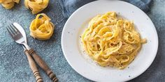 a white plate topped with pasta next to two forks