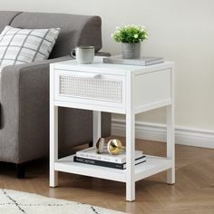 a white end table sitting on top of a wooden floor next to a gray couch