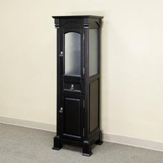 a tall black cabinet sitting in the corner of a room next to a white wall