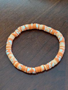 an orange and white beaded bracelet sitting on top of a wooden table