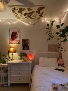 a bedroom with lights strung from the ceiling and plants on the wall above the bed